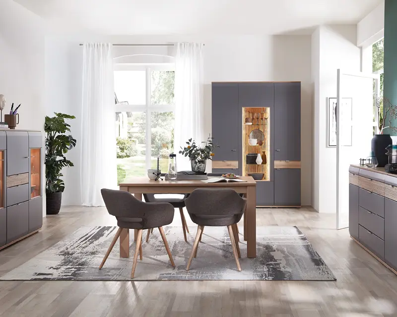 Esszimmer mit Holztisch, zwei Polsterstühlen, Vitrine und Sideboards in Grau und Holz